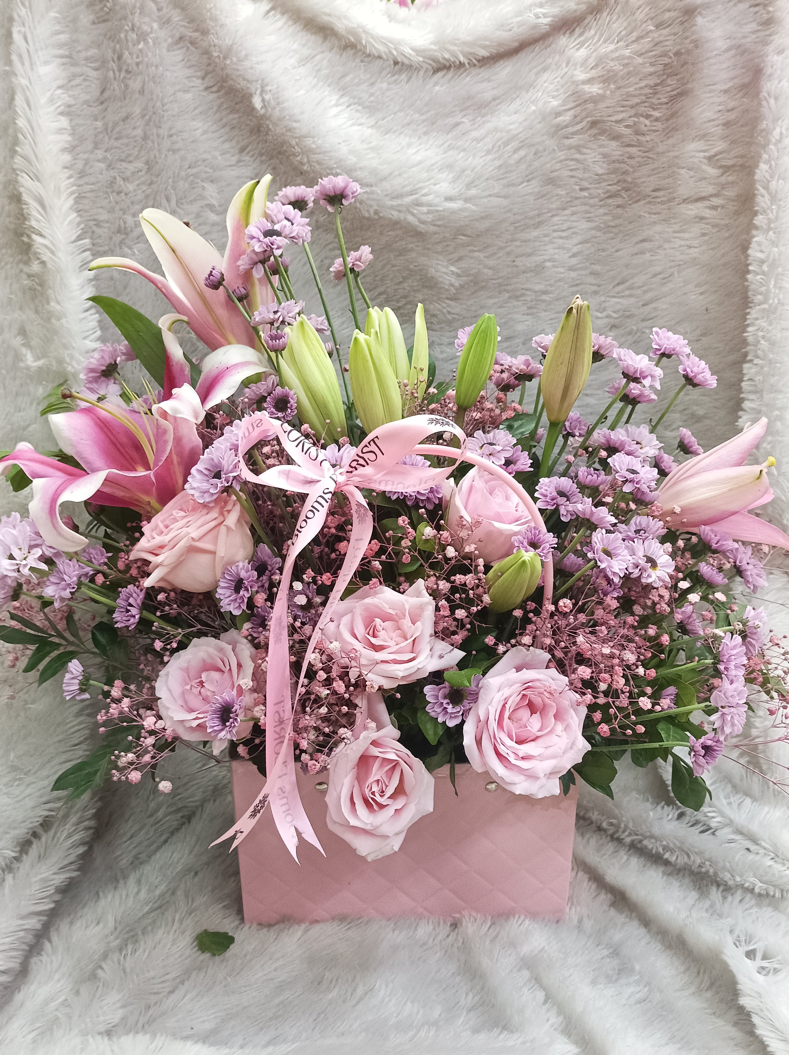 Floral arrangement with pink flowers and ribbons on a soft white background